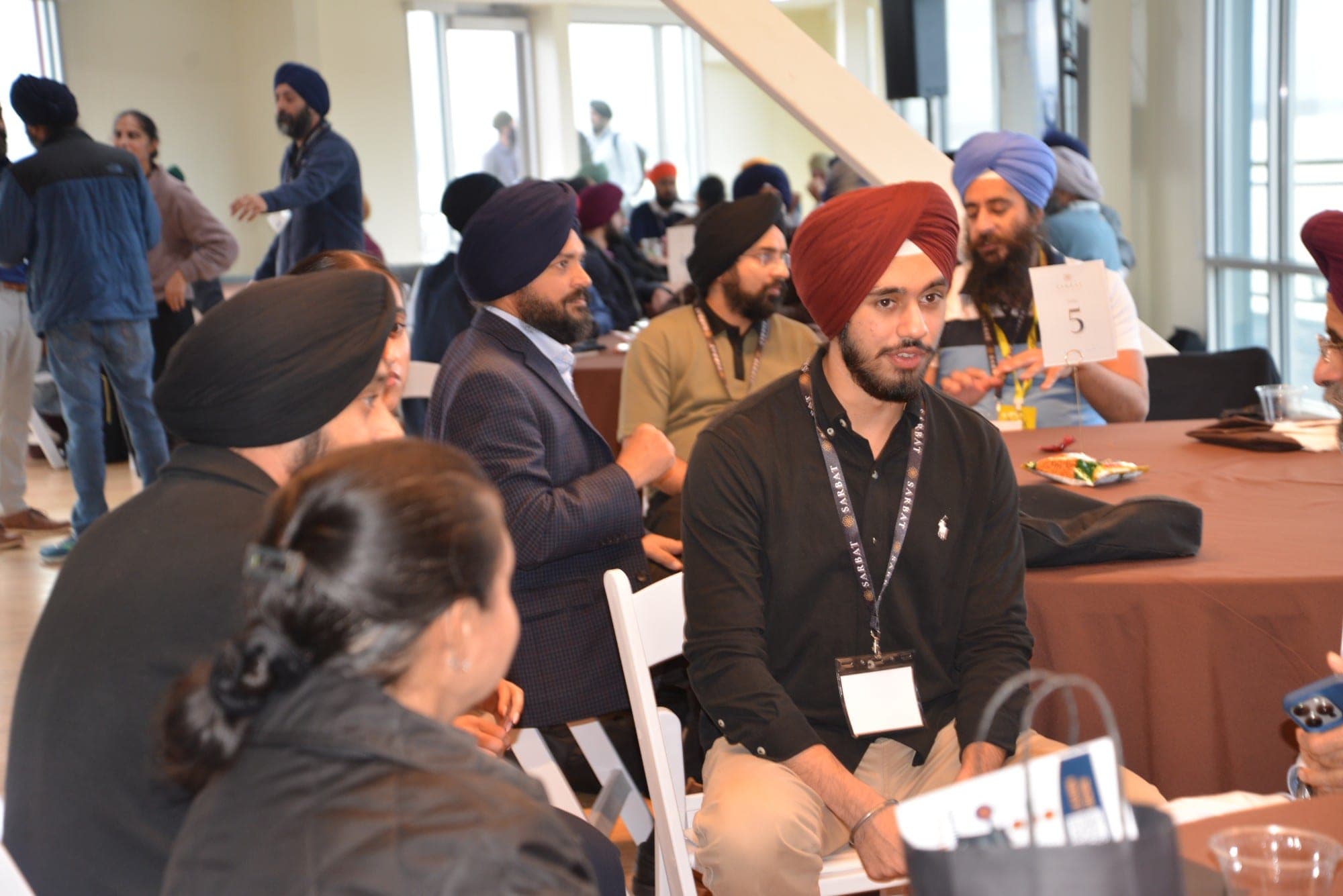 Attendees in conversation around a numbered table, one leaning in to speak.