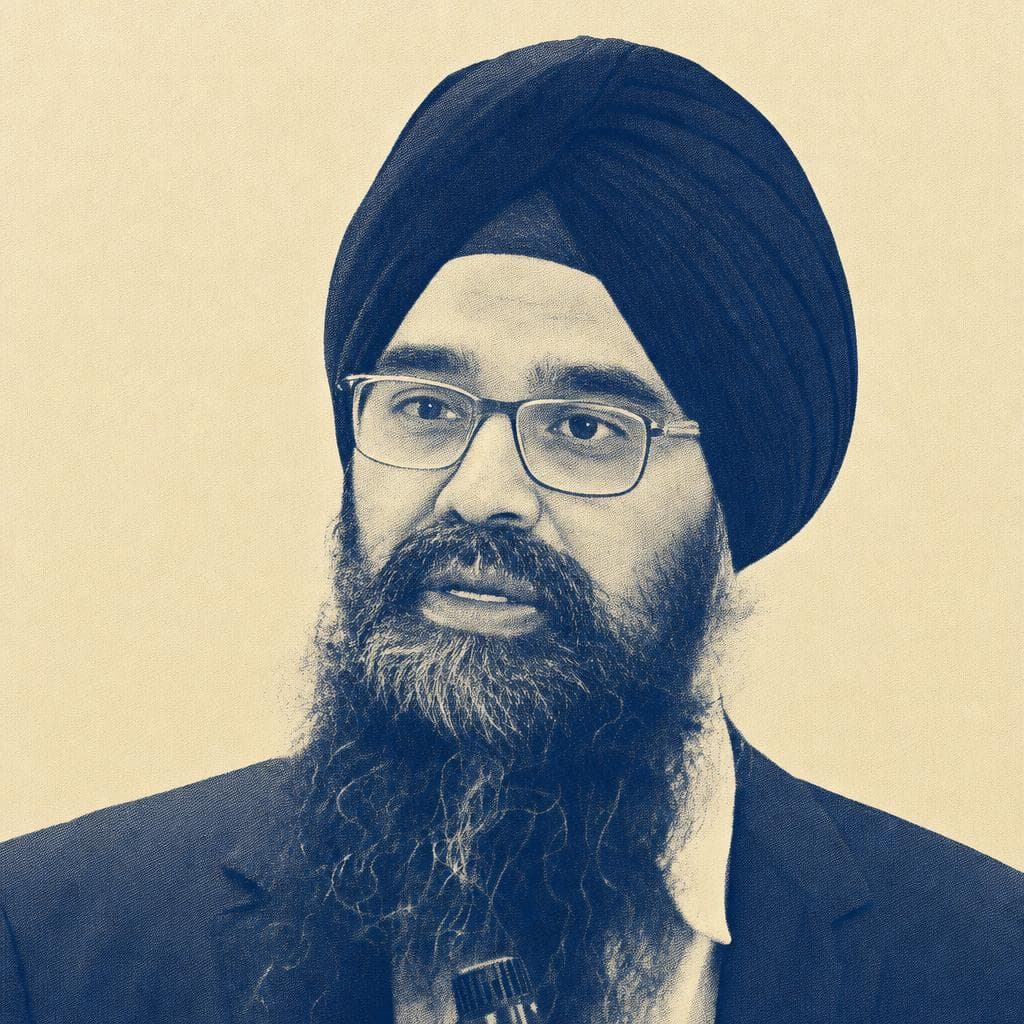 Jasmit Singh, in a navy dastar and glasses, speaking at an event.