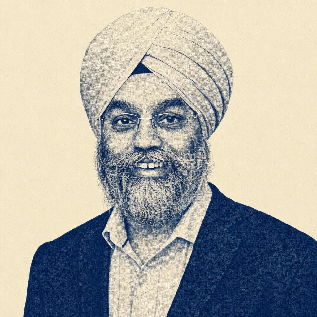 Kulmeet Singh, in a cream dastar, glasses and blazer, photographed smiling indoors.